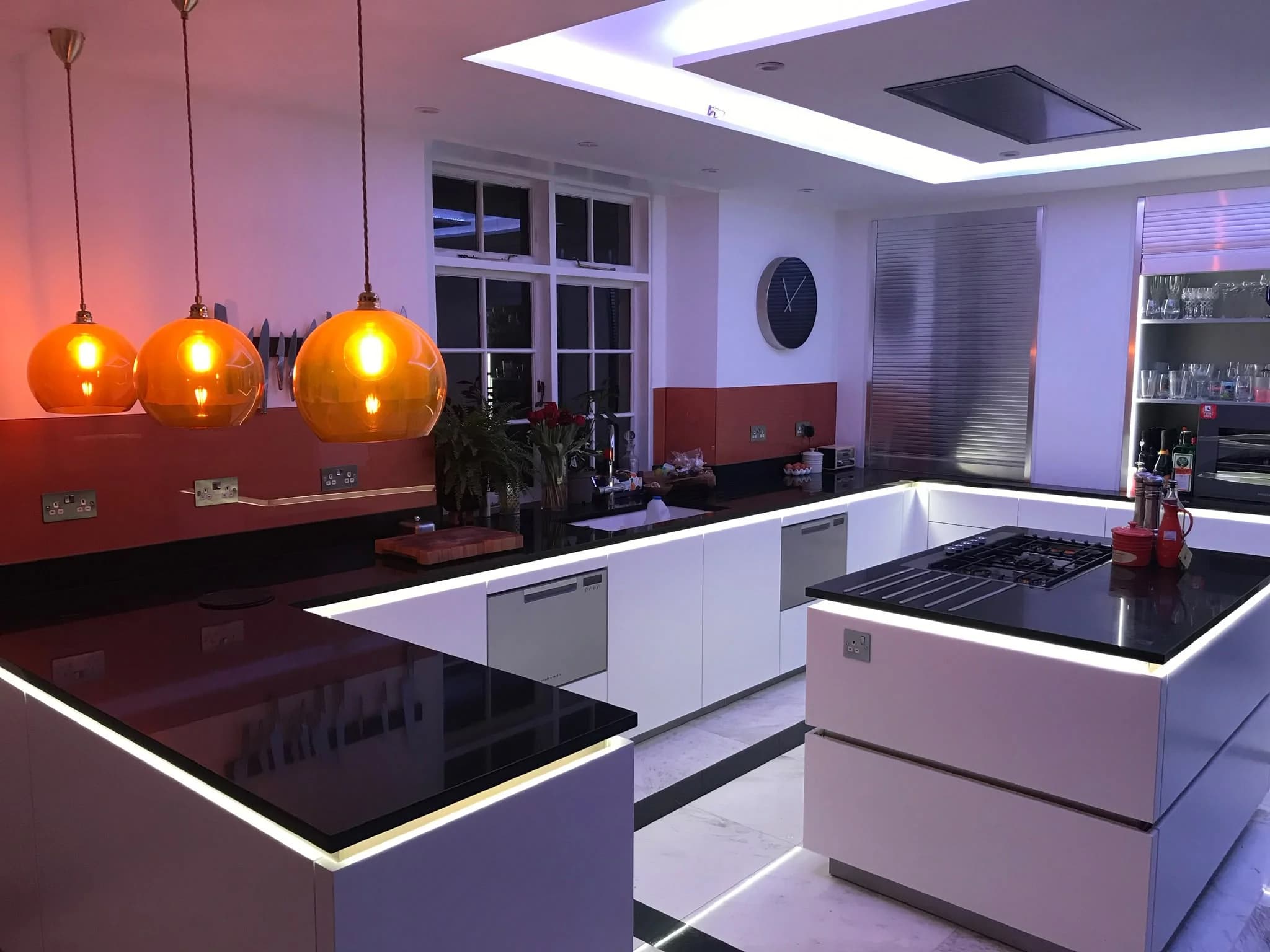 Plain Black Quartz: black quartz worktops with white cabinetry and pendant lighting
